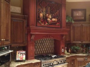 This photo illustrates how a kitchen can feature different finishes to provide a more complex look. The range hood is a paint finish with glaze and the main kitchen is a stain/ glaze finish.