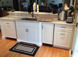 Left to right: Panelized Dishwasher, Bumped out sink cabinet with angled shaker flutes and furniture base, Ice maker with applied door panel, Trash pull out with drawer above.