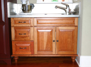 Building cabinetry which has a collected look is the current thrust in design. varied styles and finishes in different areas of a single kitchen is how that is achieved. Here you see a cherry cabinet with a stainless steel top. This serves as a sink