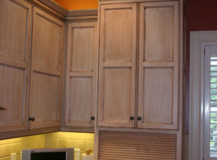 A custom made maple tamboor appliance garage is seen at the bottom of this kitchen wall tower. This enables the concealment of small appliances such as toasters and blenders, lending a sleek, clean look to the kitchen