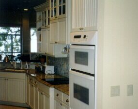 Wall cabinets are sectioned so as to provide glass doors @ the top while beadboard doors are blended with slab top drawers. Bin pulls on the drawers add to a cottage look attained in this design. This kitchen was featured in Southern Living Magazine