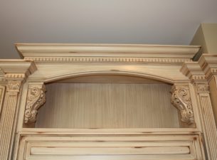 This display space features acanthus corbels which frame the left and right side of the opening along with small capitals atop the fluting. The crown molding features a dental molding rabbeted into the sub crown molding.