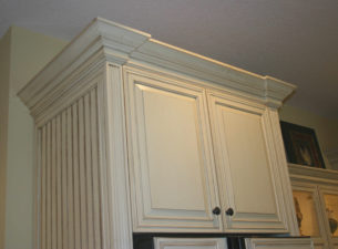 This upper cabinet is placed between 2 fluted columns and is held back 3/4" which makes the crown molding step out around the flutes for a striking effect. The left fluted panel is shown with an applied beadboard panel on the side.